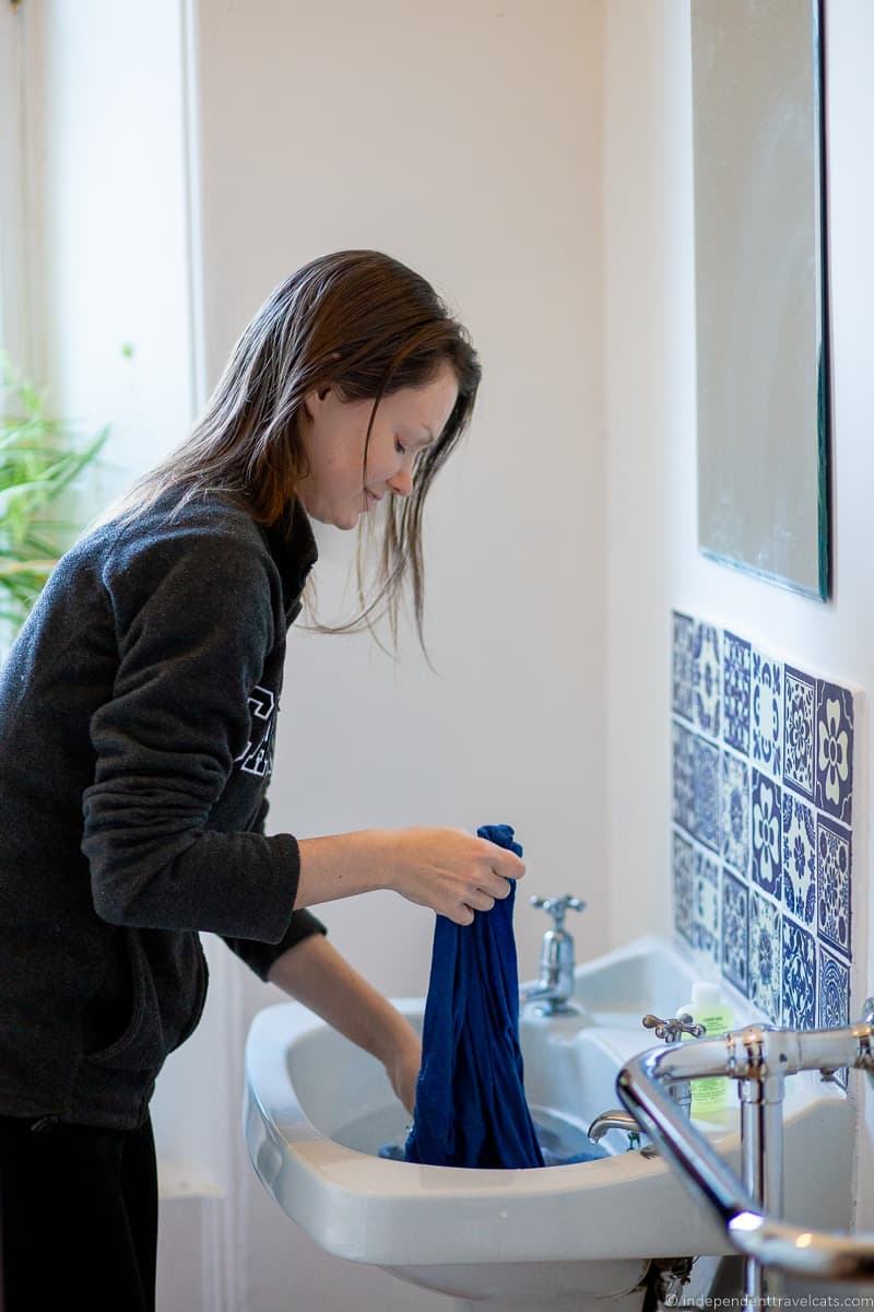 hand washing in sink doing laundry while traveling travel laundry tips