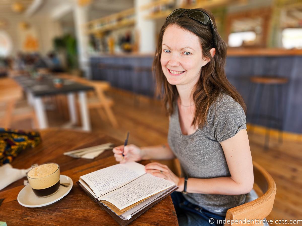 woman writing in journal at cafe best travel journal for travelers